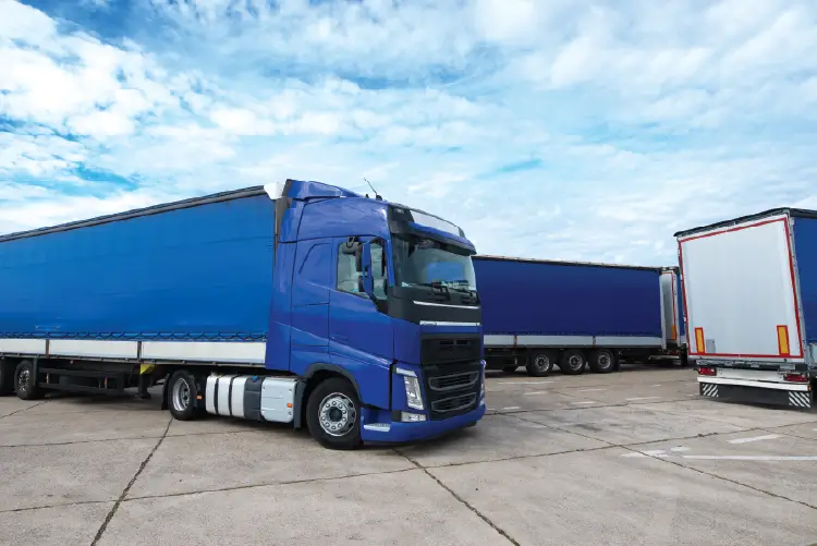 freight trucks parked in a logistics yard under a partly cloudy sky, representing comprehensive freight services in South Australia