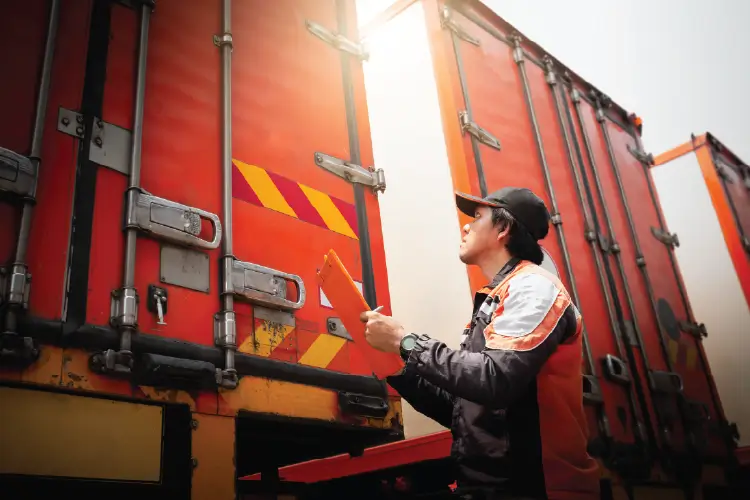 A freight worker inspecting and documenting cargo on truck, ensuring secure transport from Melbourne to Adelaide..