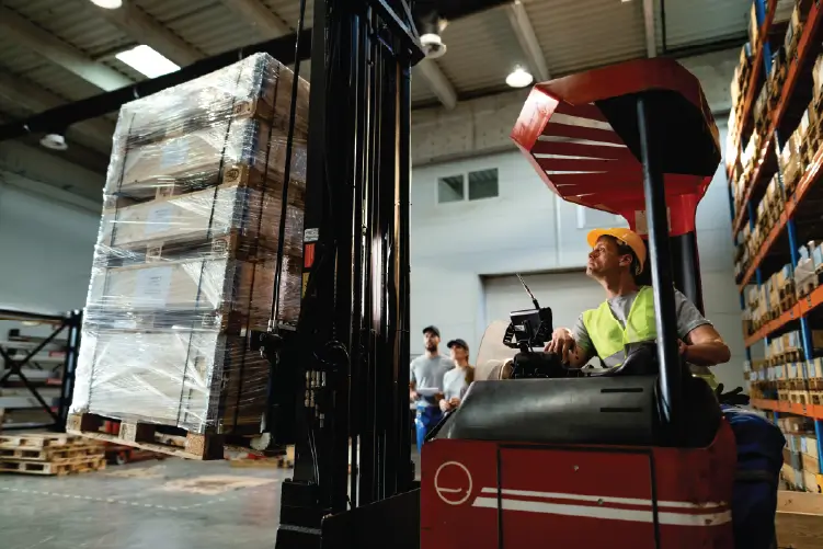 A forklift operator handling a pallet in a busy warehouse, showcasing efficient pallet delivery services in Adelaide.