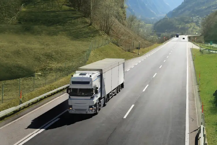 A large white truck carrying cargo travels on a highway, symbolizing interstate freight transportation from NSW