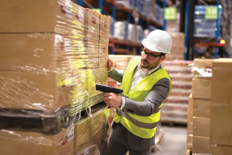 A warehouse worker in a safety vest and hard hat scanning a pallet with a barcode scanner, ensuring secure and efficient freight handling in South Australia