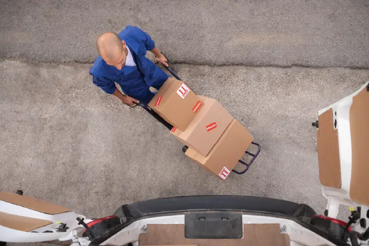 A worker carefully loading packages onto a delivery truck using a hand trolley, ensuring safe and reliable freight handling for Adelaide to Melbourne transport.