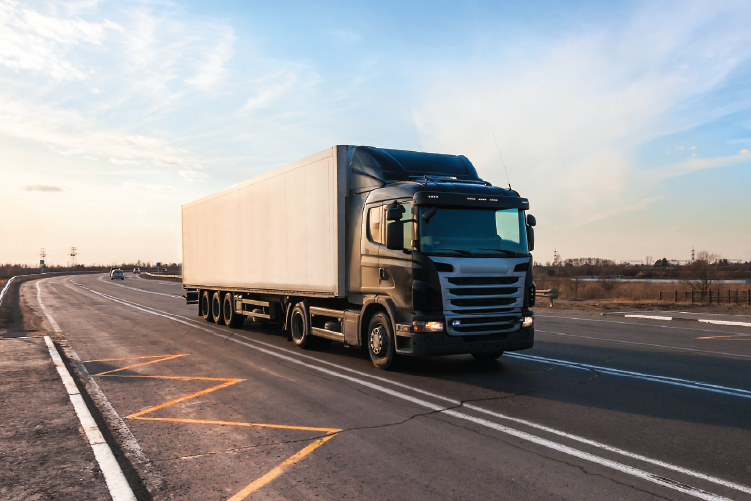 A black semi-truck with a white trailer driving on a highway, transporting freight efficiently from Adelaide to Melbourne.
